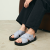 Person wearing woven sandals with black soles on a neutral background